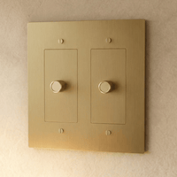 Variateur de lumière en laiton doré 2 postes sur un mur beige
