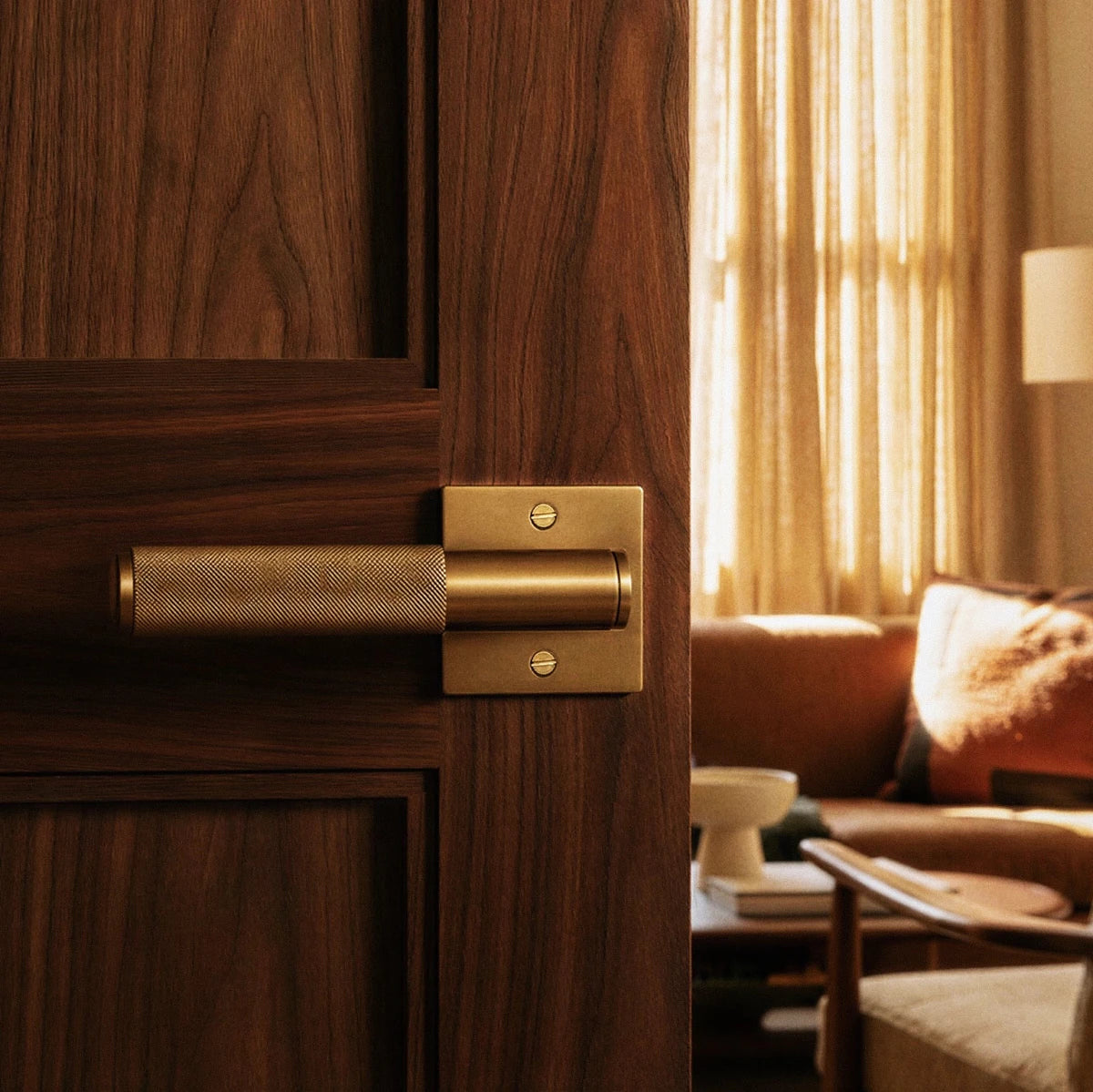 Poignée de porte en laiton brossé sur porte en noyer, ambiance salon