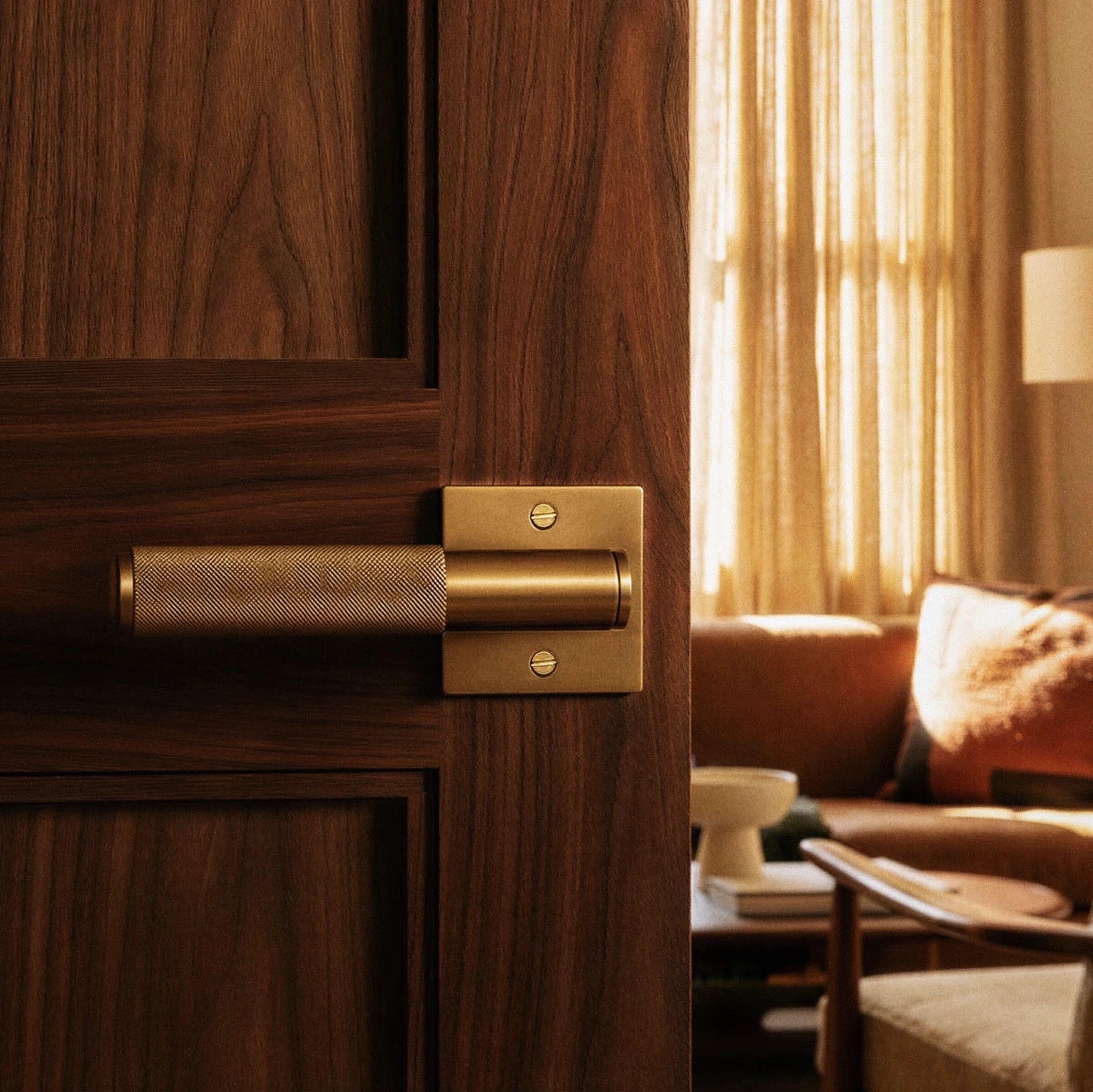 Poignée de porte en laiton brossé sur porte en noyer, ambiance salon Image