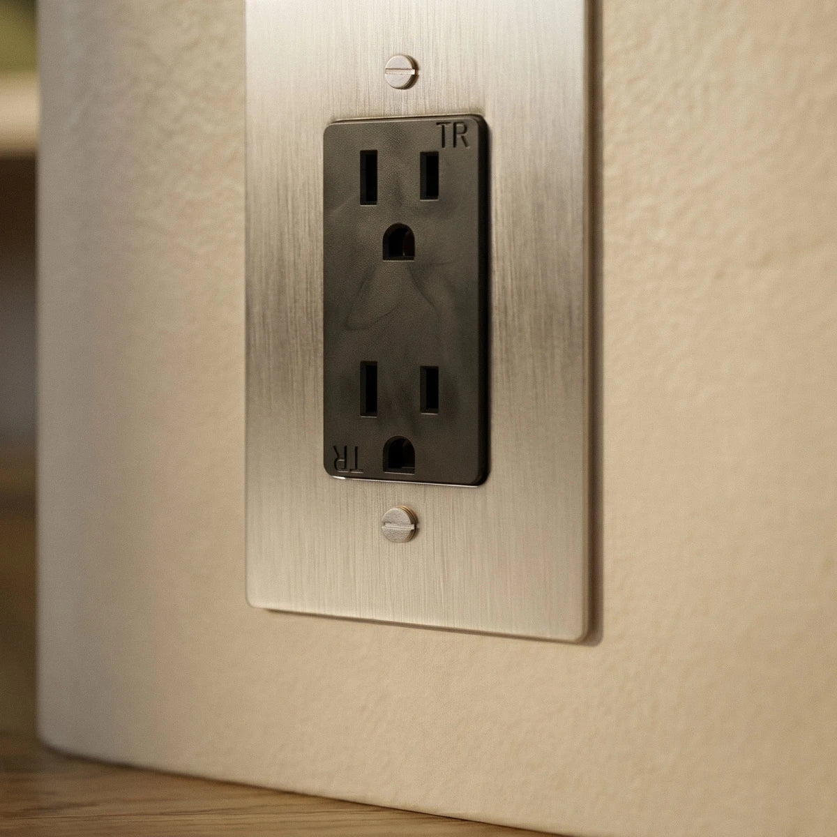 Gros plan sur une prise électrique en acier inoxydable sur un mur clair