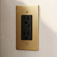 Prise électrique en laiton doré installée sur un mur clair