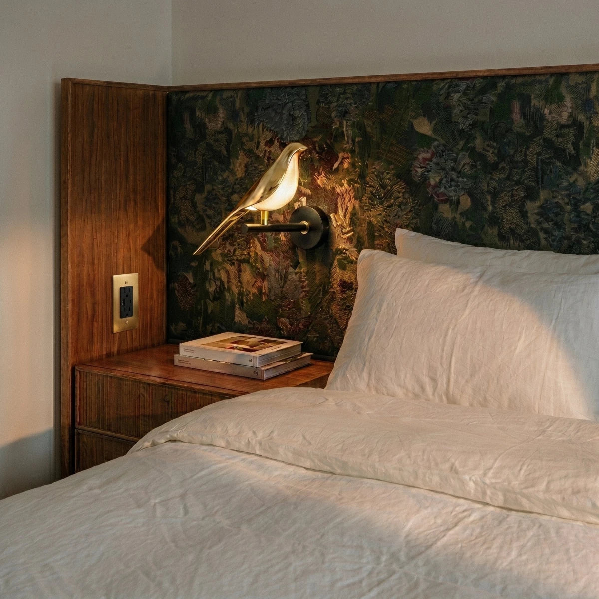 Prise électrique dans une chambre avec tête de lit en tissu vert