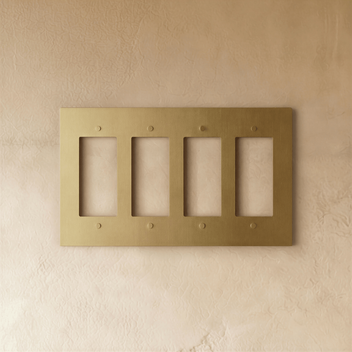 Plaque interrupteur en laiton 4 postes sur mur clair