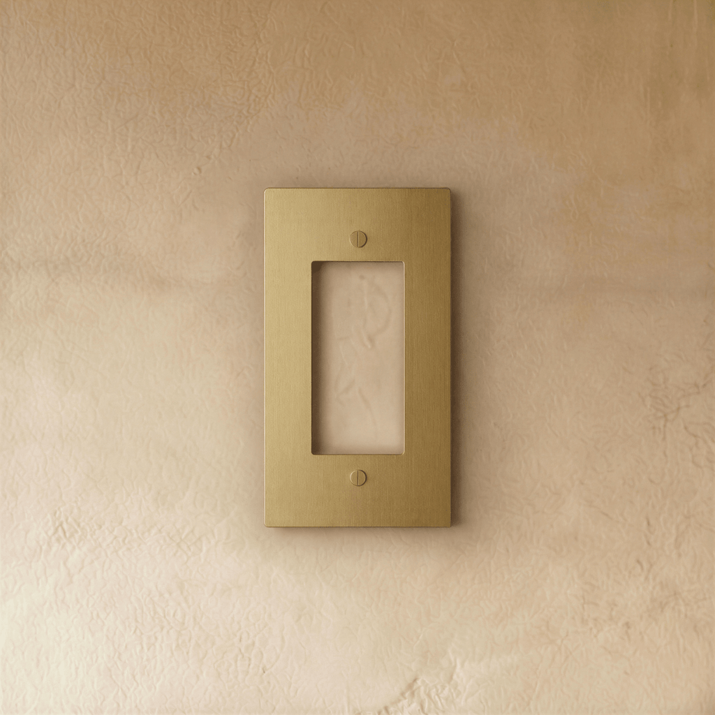 Plaque interrupteur en laiton 1 poste fixée sur un mur beige