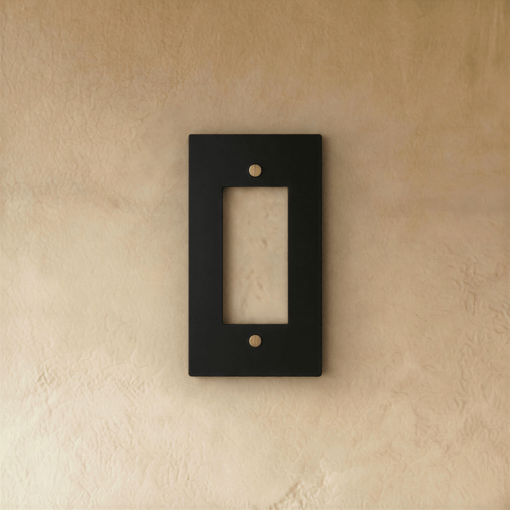 Plaque interrupteur noir et laiton 1 poste fixée sur un mur beige