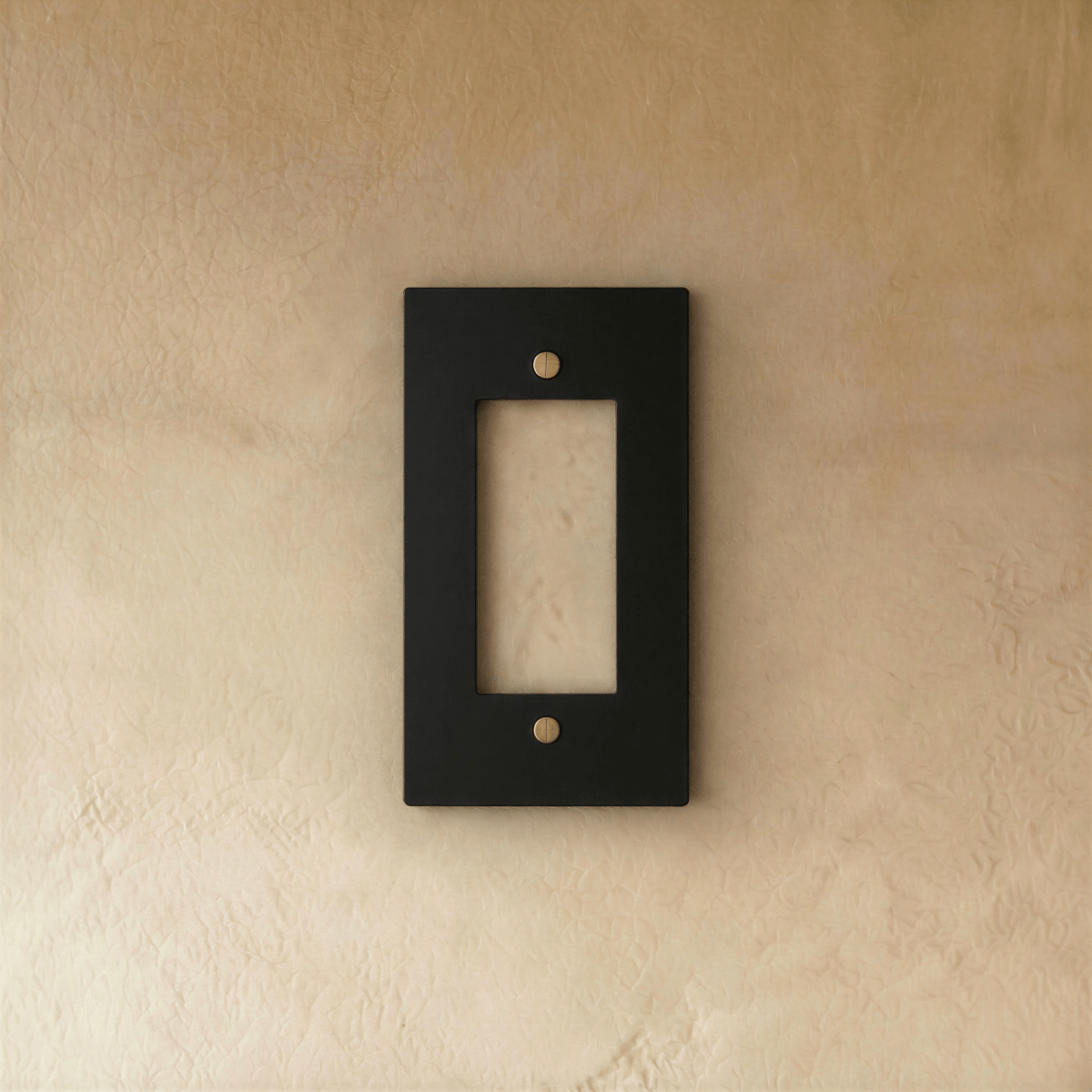 Plaque interrupteur noir et laiton 1 poste fixée sur un mur beige