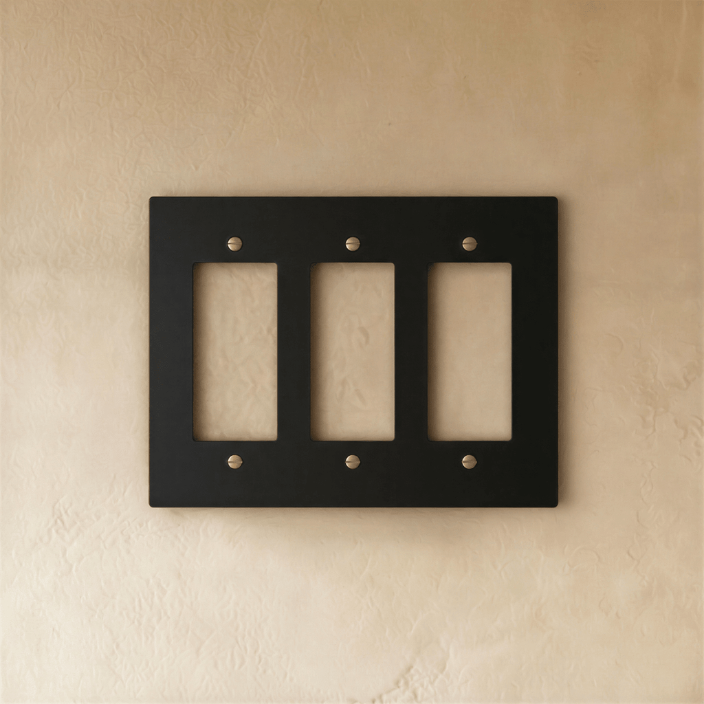 Plaque interrupteur noir et laiton 3 postes sur mur clair