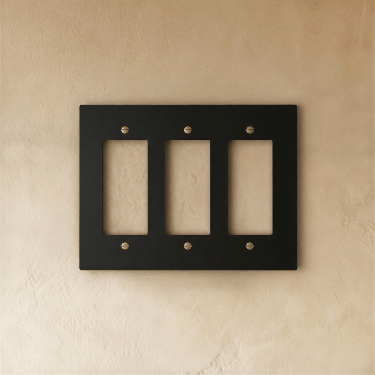 Plaque interrupteur noir et laiton 3 postes sur mur clair