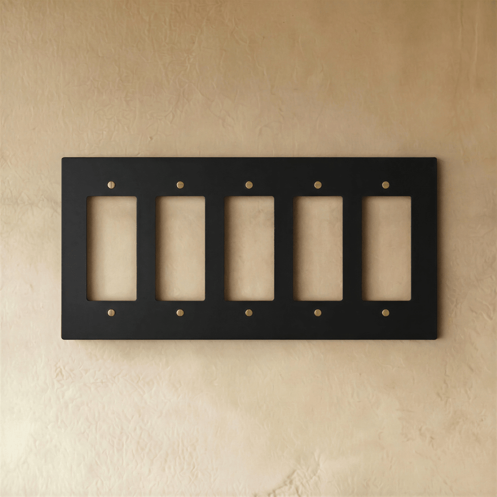 Plaque interrupteur noir et laiton 5 postes sur mur clair