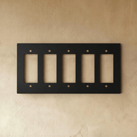 Plaque interrupteur noir et laiton 5 postes sur mur clair