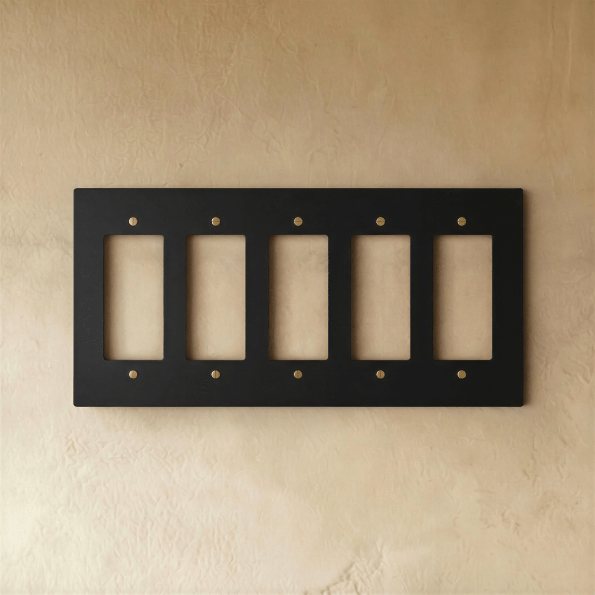 Plaque interrupteur noir et laiton 5 postes sur mur clair Image