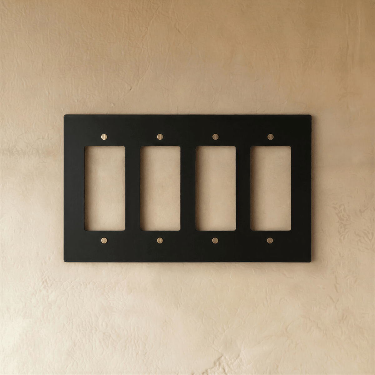 Plaque interrupteur noir et laiton 4 postes sur mur clair