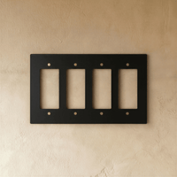 Plaque interrupteur noir et laiton 4 postes sur mur clair