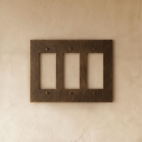 Plaque interrupteur en laiton vieilli 3 postes sur mur clair
