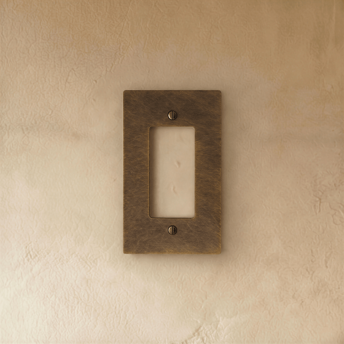 Plaque interrupteur en laiton vieilli 1 poste sur un mur beige