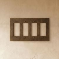 Plaque interrupteur en laiton vieilli 4 postes sur mur clair