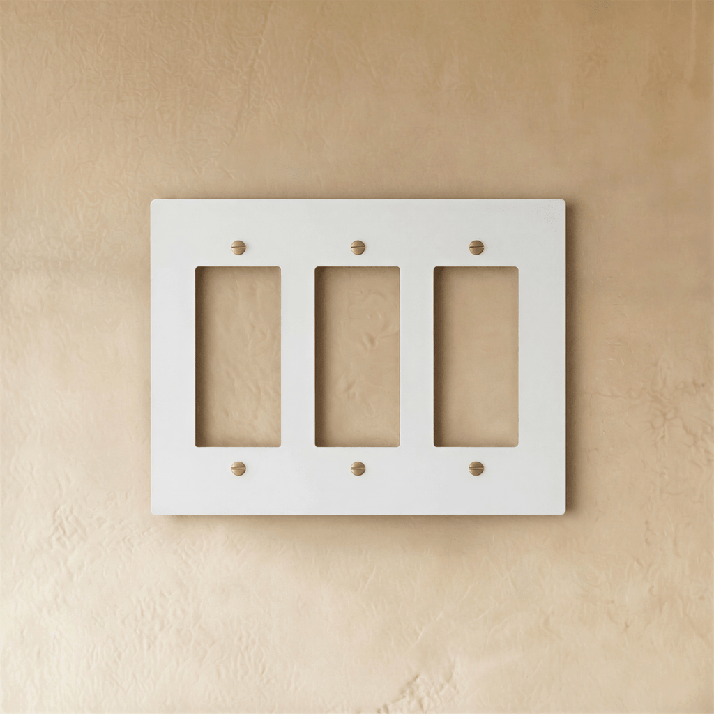 Plaque interrupteur blanc et laiton 3 postes sur mur clair