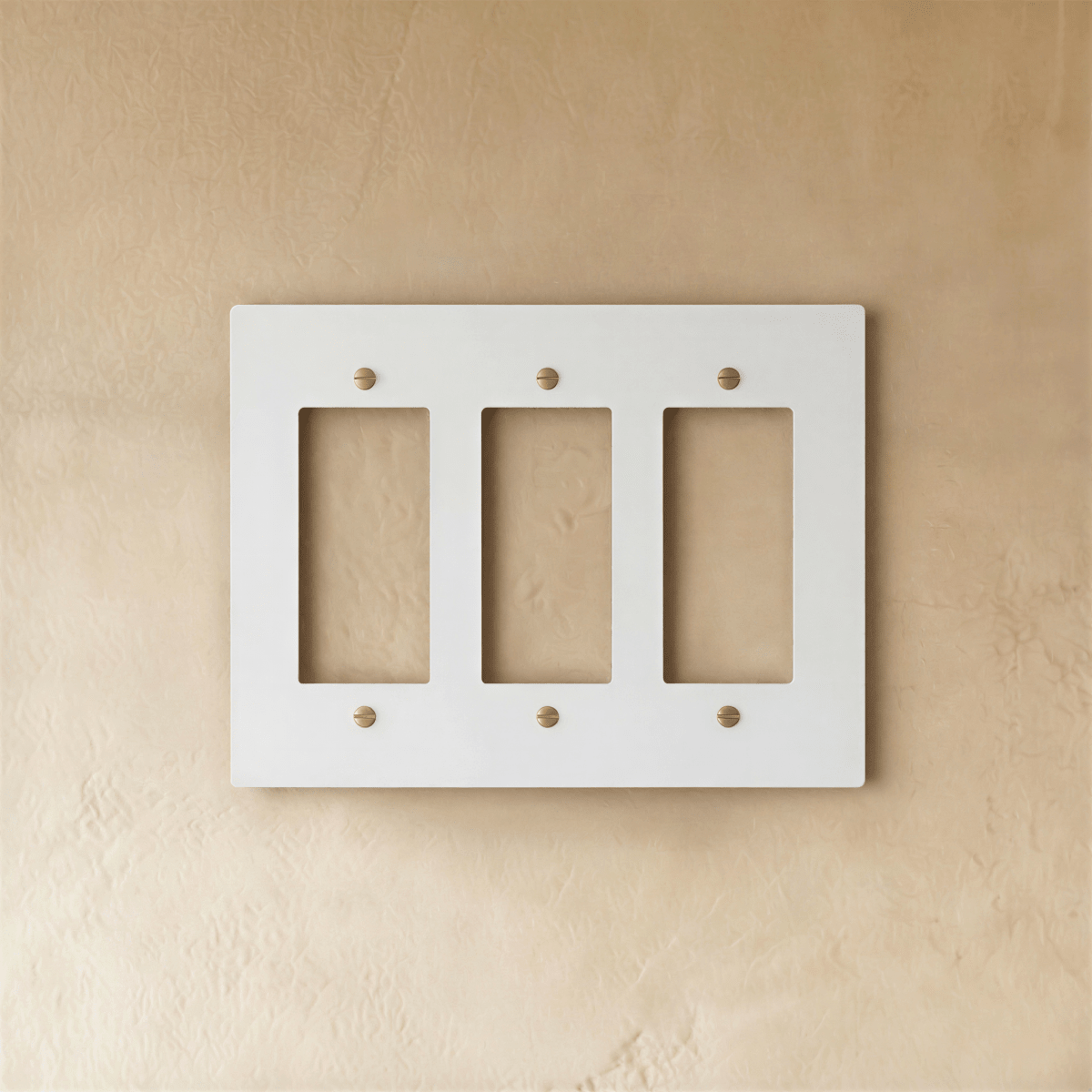 Plaque interrupteur blanc et laiton 3 postes sur mur clair