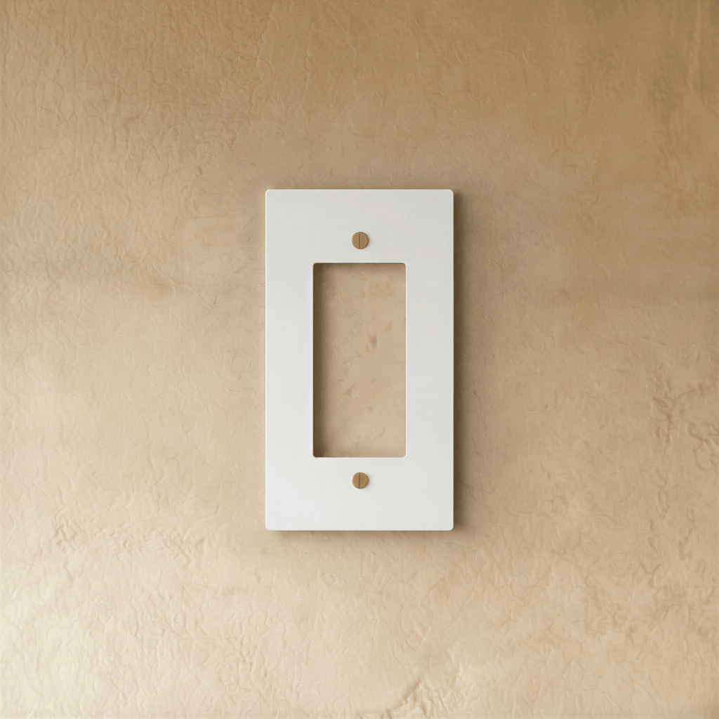 Plaque interrupteur blanc et laiton 1 poste fixée sur un mur beige
