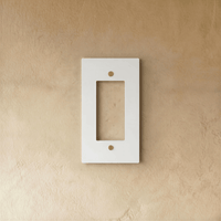 Plaque interrupteur blanc et laiton 1 poste fixée sur un mur beige