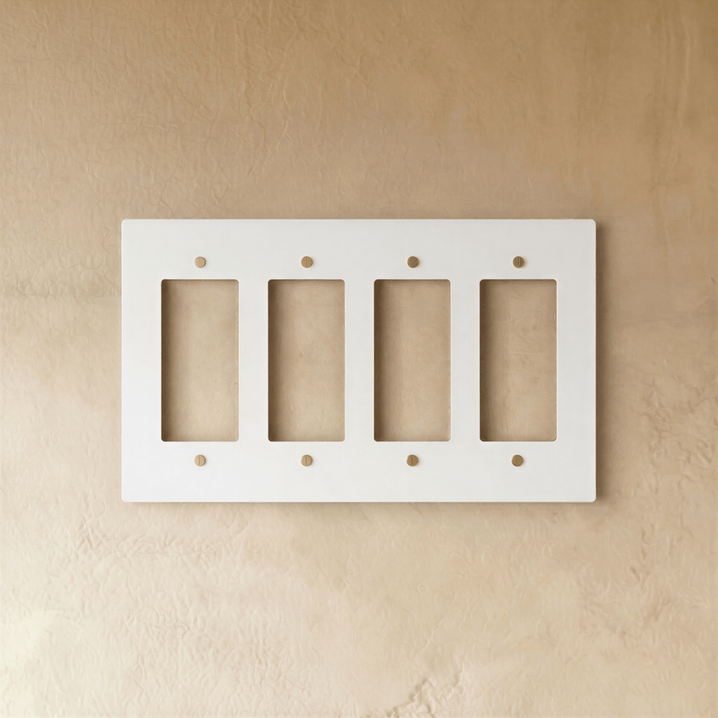 Plaque interrupteur blanc et laiton 4 postes sur mur clair