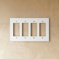 Plaque interrupteur blanc et laiton 4 postes sur mur clair