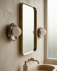 Applique murale en marbre en duo autour d'un miroir en laiton dans une salle de bain