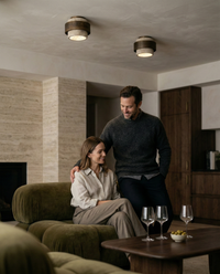 Deux plafonniers bois et travertin allumes au plafond d'un salon chaleureux